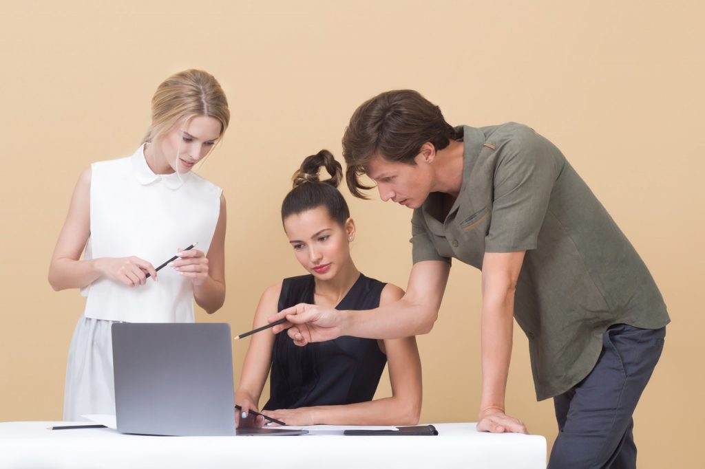 three people discussing data on a laptop